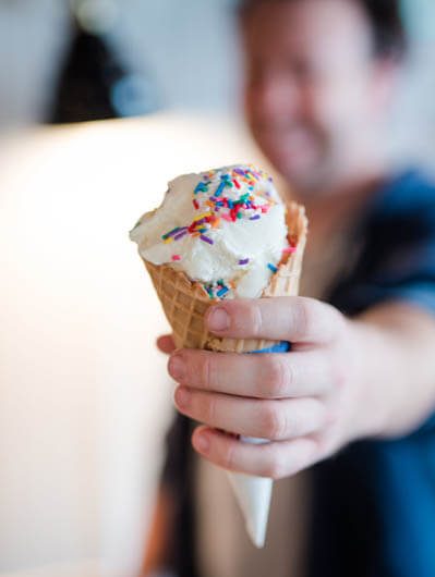 Close-up view of man holding a cone of ice-cream with sprinkels