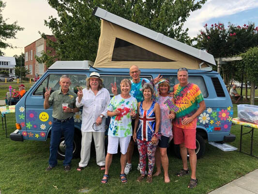 Lovefest group photo of people standing in front of a painted van, wearing colorful clothes