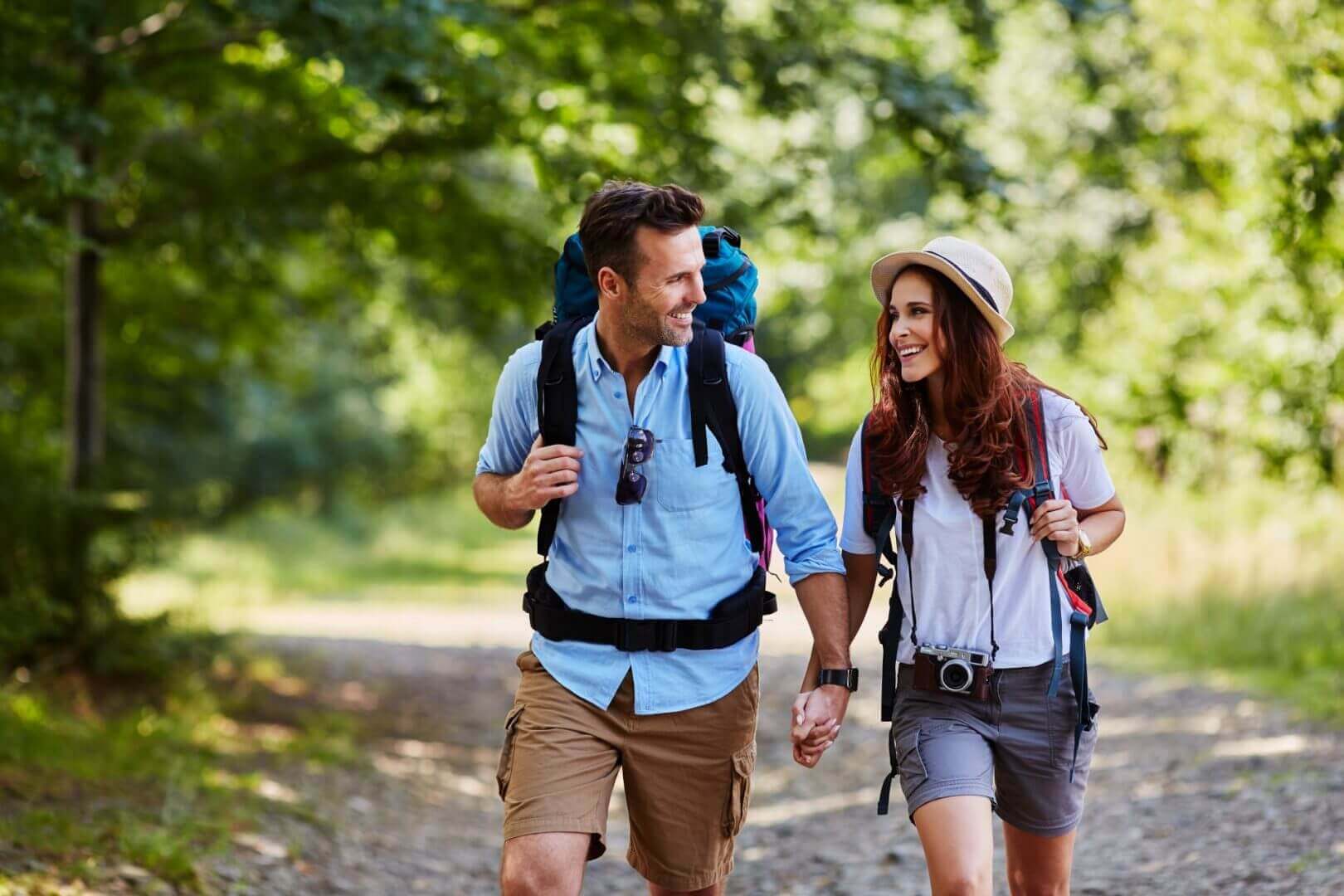 Happy couple hiking together in mountains with backpacks